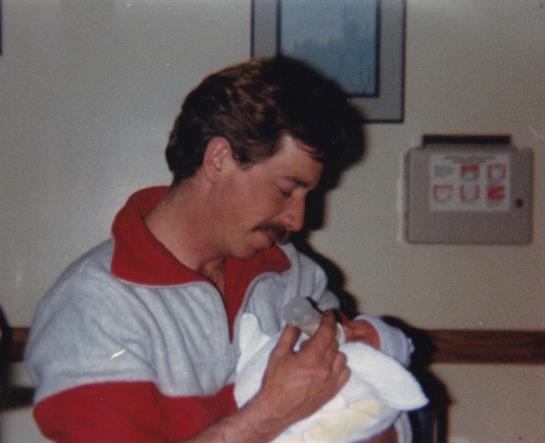 A father tenderly holds his newborn in a hospital, cherishing a special family moment.