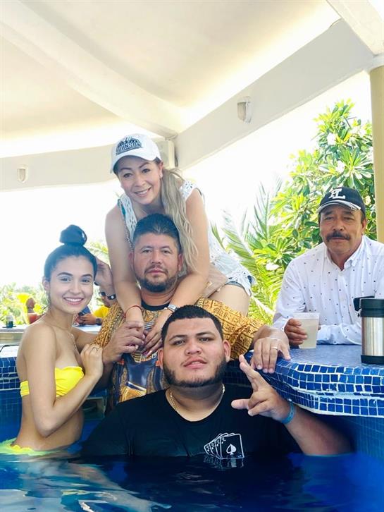 Five friends are gathered by a beautiful pool, relaxing and enjoying each other's company outdoors.