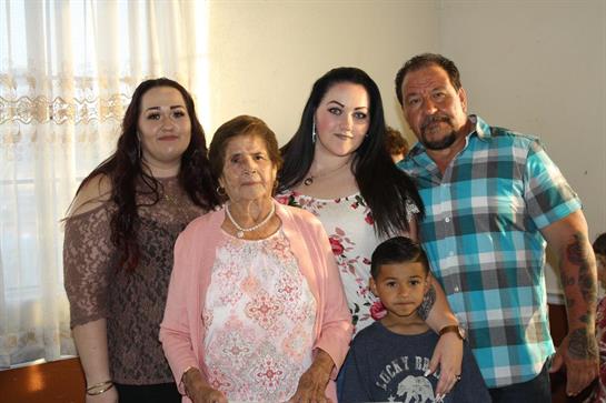 Five family members pose together in a warm and inviting living room, smiling happily.