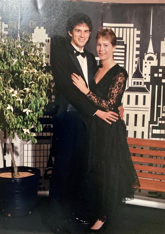 A couple enjoys a moment together dressed in formal attire, showcasing a classy urban backdrop.