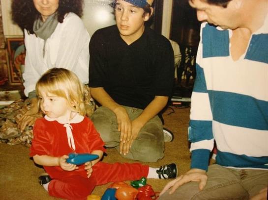 Children enjoy playing with colorful toys while adults engage in conversation in a cozy living room.