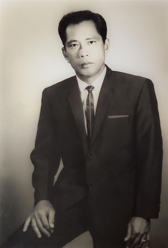 A man in a classic suit stands confidently with a slight smile, reflecting a timeless fashion sense.