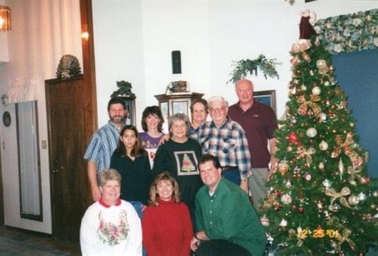 Family gathers by a festive Christmas tree, sharing joyful moments this holiday season.