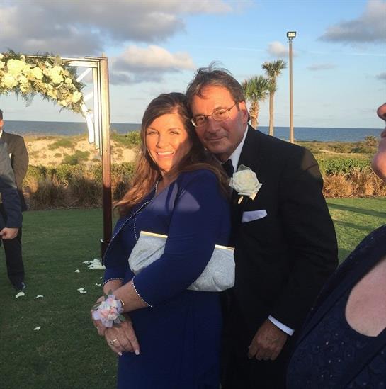 Couples and guests celebrate a wedding at a scenic beachside venue during sunset.