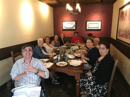 Friends sit around a large table sharing food and conversation in a warm, inviting restaurant.
