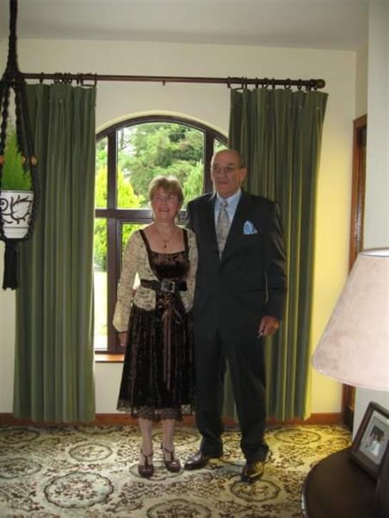 A couple in traditional attire stands together amid warm lighting and stylish decor.