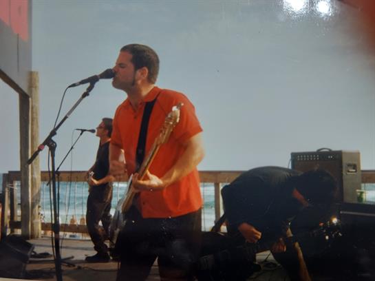 Musicians perform energetically on stage with a stunning ocean view, creating a vibrant vibe.