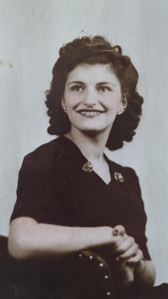 A stylish young woman smiles in a vintage black dress, exuding elegance and charm.