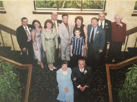 Group of family members posing for a photo at a formal event in a beautifully decorated hall.