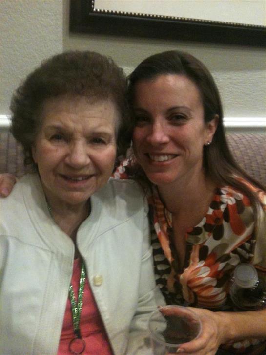 Two women share smiles, embracing each other warmly during a family gathering at home.