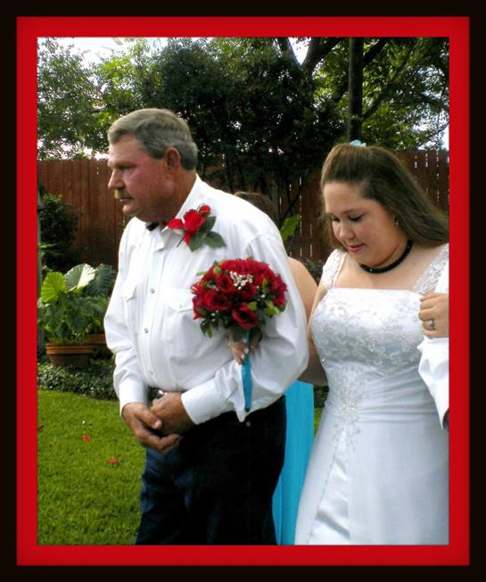 Bride elegantly dressed holds flowers while walking with her father in a lush garden.
