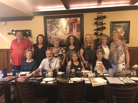 A group of friends joyfully reunites around a table, sharing laughter and a meal together.