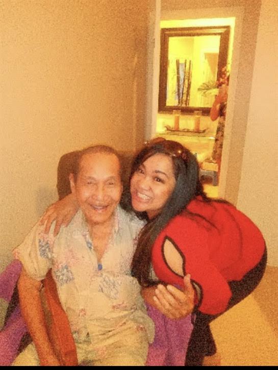 A joyful woman embraces an older man in a warm and welcoming living space, enjoying time together.