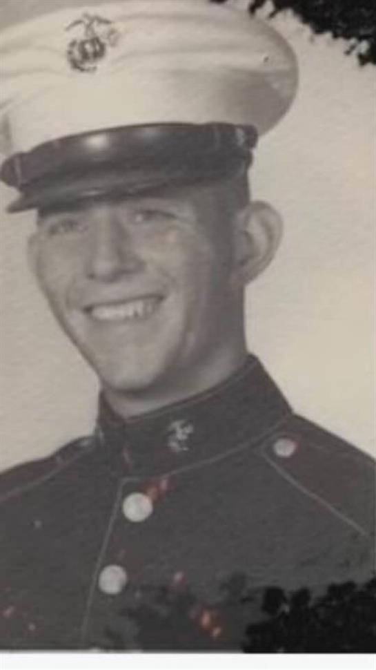 A young soldier is smiling proudly while wearing his military uniform with a hat.