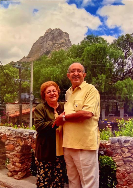 Two happy individuals pose together in a picturesque outdoor setting, smiling broadly.