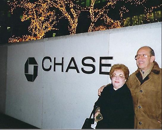 Two people pose happily outdoors against a lit background, embracing in a festive mood.
