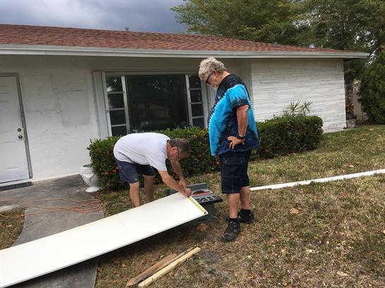 Two individuals are preparing materials for a home renovation in front of a house.