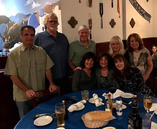 A group of friends enjoys a happy reunion, smiling and sharing moments at the table.