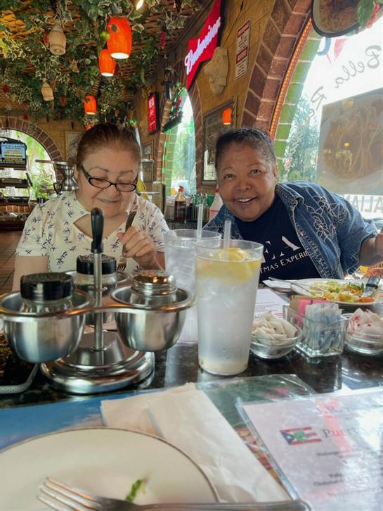 A couple is having lunch at a lively restaurant, sharing laughter and food together.
