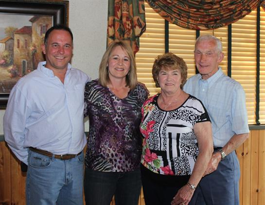 Four family members are standing together in a welcoming room, enjoying a moment of togetherness.
