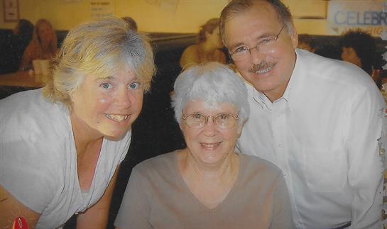 Three family members share smiles and laughter during a casual gathering at a restaurant.