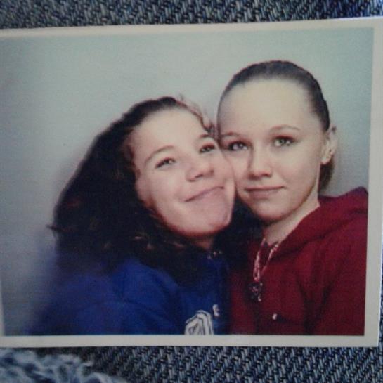 Two friends take a close-up picture in a photo booth with joyful expressions.