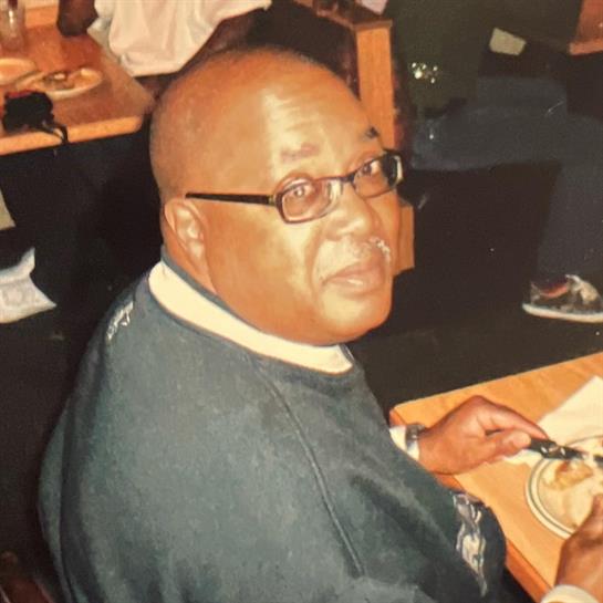 An elderly man sits at a dining table in a restaurant, savoring his meal amidst lively surroundings.