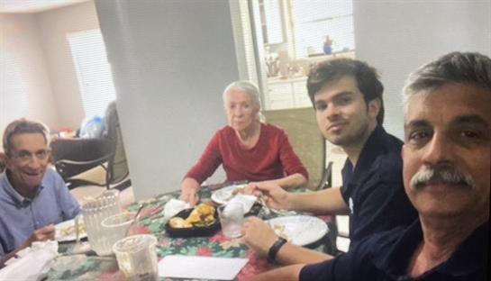 People gather around a table filled with food, sharing laughter and conversation during lunch.