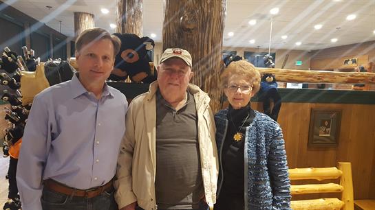 Three friends pose together in a cozy lodge filled with rustic charm and warmth.