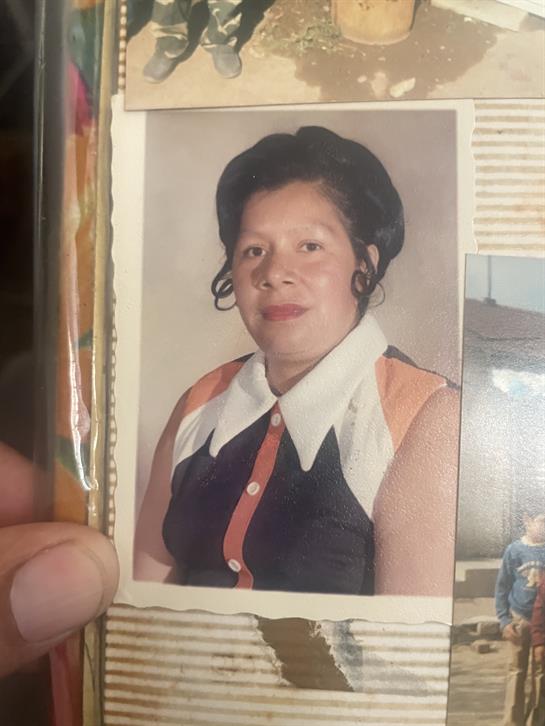 A woman smiles in a stylish blouse with colorful buttons and a vintage hairstyle.