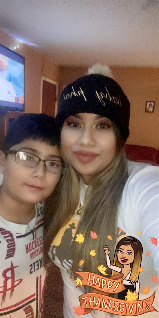A mother and her son smile for a close-up shot while relaxing indoors at home.