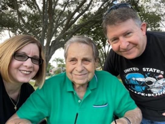 Three family members share joyful moments outdoors on a bright sunny day in the park.