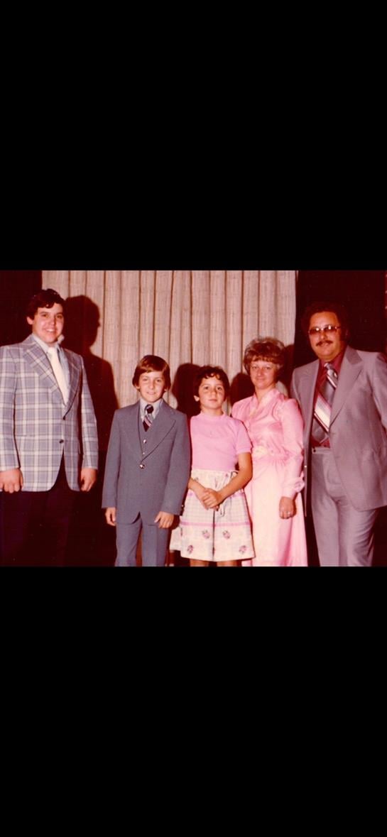 Gathered at a hall, a family dressed in formal clothing poses joyfully during a special event.