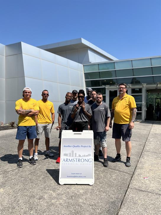 A group of workers stands proudly outside a contemporary structure under clear blue skies.