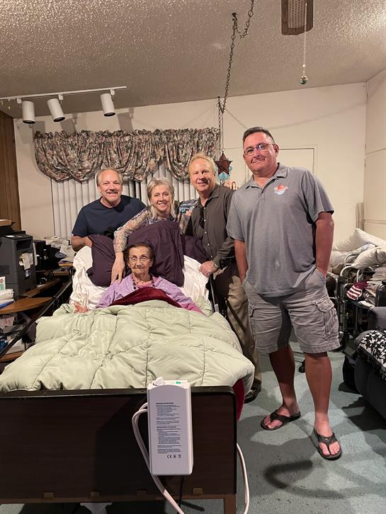 A family unites joyfully around a relative in a hospital bed during a heartfelt visit.