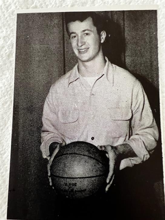 A young basketball player poses with a ball, embodying passion for the sport in a retro setting.