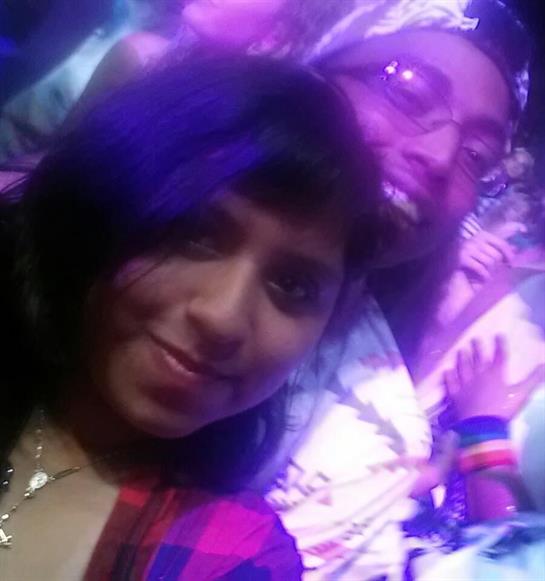 Friends enjoy a lively concert atmosphere while taking a selfie amidst colorful lights.