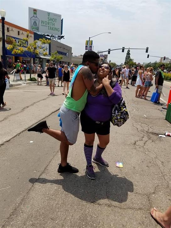 A couple joyfully embraces at a lively street festival full of activity.