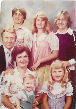 A family poses together in a studio for a portrait from the late 1970s.