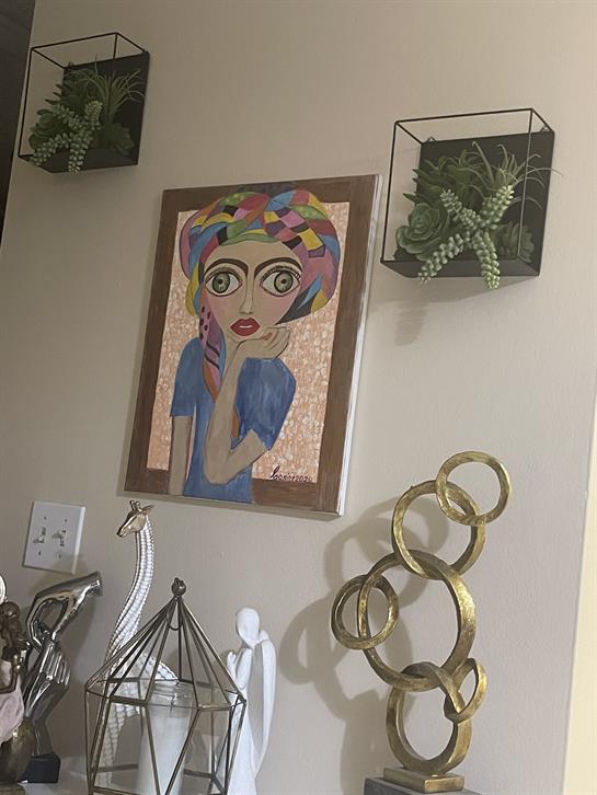 Vibrant mosaic art piece mounted on a wall alongside decorative plants and elegant sculptures.