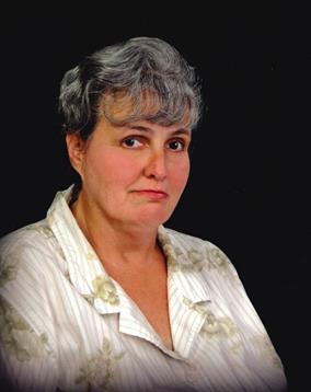 A woman with gray hair and a floral blouse gazes at the camera with a thoughtful expression.