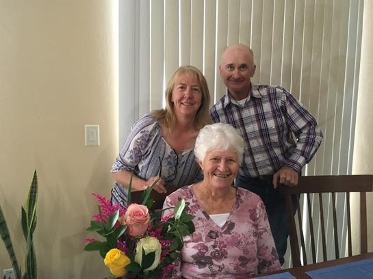 Family members gather in a home, sharing joy and conversation while surrounded by flowers.