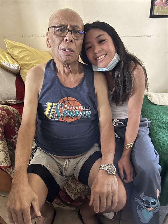 A girl and her grandfather smile together at home, enjoying quality time.