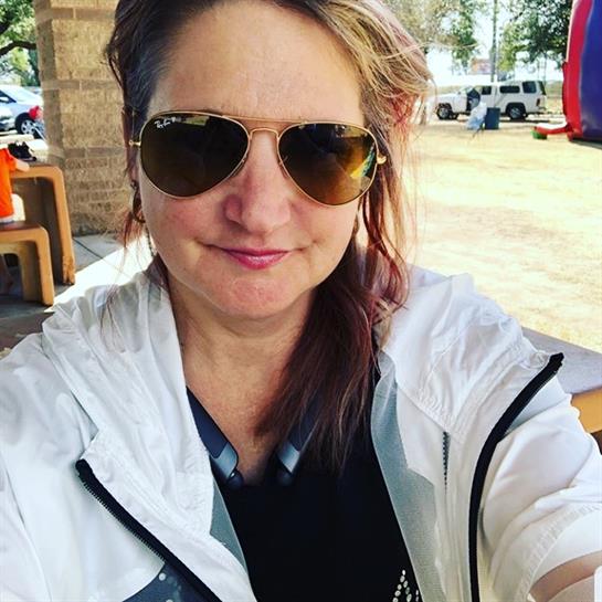 Woman poses for a picture at an outdoor gathering, enjoying the warm weather and community vibe.