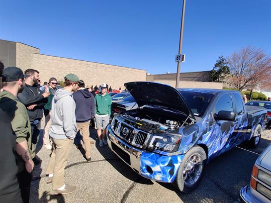 Enthusiasts admire a modified truck showcasing its unique design and engine modifications.