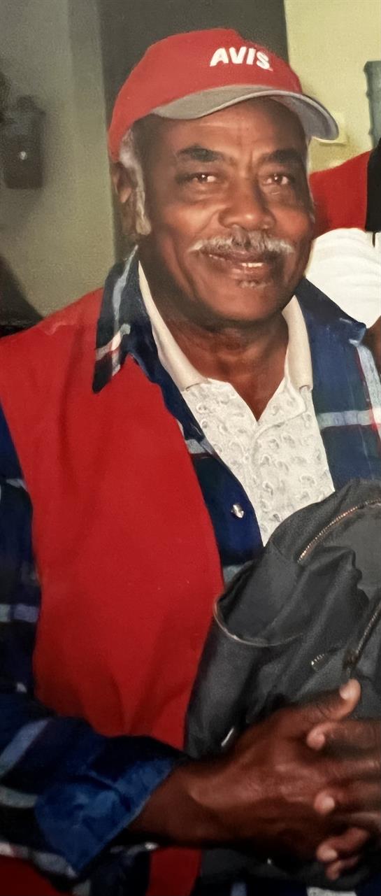 Elderly man with bright clothing smiles joyfully while sharing moments with friends indoors.