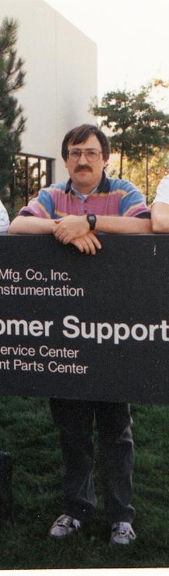 Two employees pose by a customer support center sign, enjoying a break during a sunny afternoon.