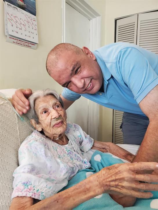 Man embraces elderly woman in a comfortable living area, showcasing their close relationship.