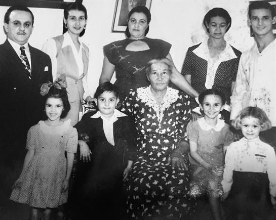 A group of family members poses together in a cozy vintage home, showcasing multiple generations.