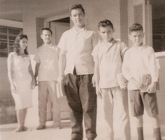 Five family members pose together in a nostalgic outdoor setting, smiling and interacting.